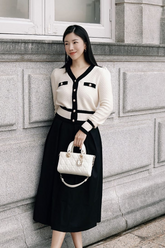 a lady in a white cardigan with black trim and a black skirt